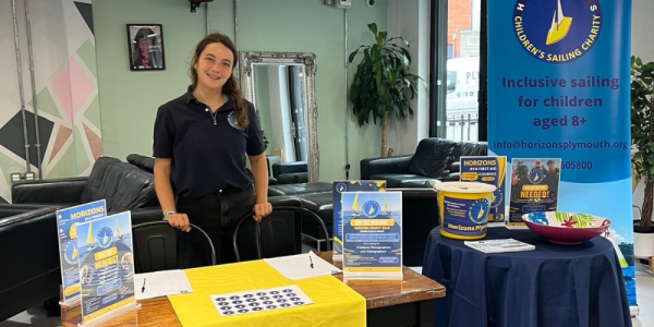 Horizons team member standing with a information stall about the charity